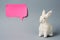 White Easter bunny with pink sticky note on gray background decoration animal Copy Space