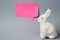 White Easter bunny with pink sticky note on gray background decoration animal Copy Space