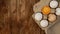 White eggs carton and cracked egg half with yolk top view on wooden background