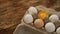 White eggs carton and cracked egg half with yolk top view on wooden background