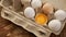 White eggs carton and cracked egg half with yolk top view on wooden background