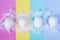 White eggs and feathers on colorful polka dots background. Happy Easter concept. Minimal style, flat lay. Close up