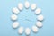 White eggs in the form of wall clocks on a blue background. Concept, timing, over time. Top view, flat lay.