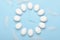 White eggs in the form of wall clocks on a blue background with feathers. Concept, timing, over time. Top view, flat lay