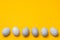 White eggs in a row at bottom of yellow background with copyspace. easter minimalist concept design