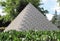 White Egyptian pyramid in the green summer park