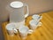 White electric kettle and four white ceramic mugs with teaspoons on wooden table