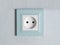 White electrical outlet with blue piping on the wall, close-up. European type sockets, the concept of construction work