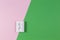 White electrical socket on light pink and green color background