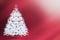 A white, elegant Christmas tree with a red star and round toys with snowflakes. Gradient red background. Christmas card