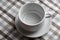 A white empty teacup stands on a table with a brown klechaty tablecloth