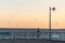 white empty wooden bench on pier by sea or ocean water, tranquility and serenity concept, calm sunset scene