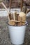 White enamel bucket filled with brooms and brushes for cleaning