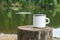 White enamel mug mockup with tree stump