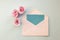 white envelope, blue blank card, three pink rose flowers on a blue background. Minimal Flat lay
