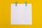 White envelope with green clothespins on a yellow background.