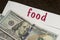 White envelope with the inscription food and dollar bills lie on a wooden table. Manage your finances and save money concept.