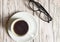 White espresso Cup and black stylish glasses on wooden background, top view, business concept pause