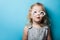 A white European little girl in toy glasses looks interested at a blue background