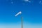 White extended Windsock on wooden pole against blue sky on the b