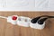 White extension cord with power button and four outlets on the floor. Electric power strip with switch for home or office.