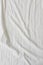 White fabric texture background. Wrinkled, crumpled fabric. Top view of unmade bed sheet after night sleep. Soft focus