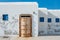 White facade of the dock building with traditional blue windows and old rusty door on Andros island, Greece