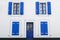 White facade house with blue windows and shutters, open and closed shutters