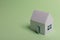 White family paper house in man hand on mint background paper. Minimalistic and simple concept, style. Copy space. Horizontal