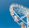 White Ferris wheel isolated on blue sky at the background.