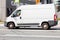 White Fiat Ducato speeding on road. Cargo delivery panel van in motion on the street, side view