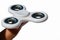 White fidget spinner toy balancing on index finger of adult male person, white background