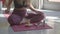 White fit yogui woman sitting on a pink yoga matt, lighting up a candle and sage leaves for aroma therapy. Wearing pink