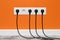 White five-way wall power socket on orange wall