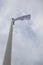 White flag on the mast near the beach. Flag on a background of cloudy sky