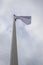 White flag on the mast near the beach. Flag on a background of cloudy sky