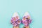 White flat female shoes filled with pink daisies and wildflowers on pastel blue background