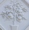 A white floral plaster relief on a white plastered wall