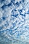 White, fluffy altocumulus clouds on a clean, blue summer sky.