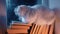 White fluffy cat resting atop pile of paper books, night rain in window, autumn