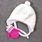 White fluffy children`s hat with ties and pink small mittens. The concept of winter warmth and comfort