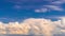 White fluffy clouds move quickly across the blue sky.