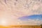 White fluffy clouds and a Sunny background with a thin strip of flat landscape