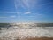 White foam of waves at the sea, wide blue sky. Summer time, Matalascanas, Spain