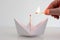 White folded paper boat with unlit match on top and Caucasian ma