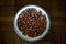 White food bowl on laminate floor filled with cat food