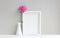 White frame, empty mock-up, beside vase with pink aster