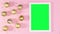 White frame with green screen and gold Christmas ornaments on pastel pink theme. Stop motion