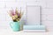 White frame mockup with chamomile and purple flowers in mint green pitcher and books