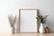 White frame mockup on table. Small white vase with dry leaves and grass.